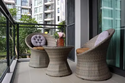 a balcony with three wicker chairs on a balcony at Cassia Residences by NLA in Bang Tao Beach