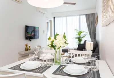 a dining room table with glasses and a vase of flowers at Cassia Residences by NLA in Bang Tao Beach