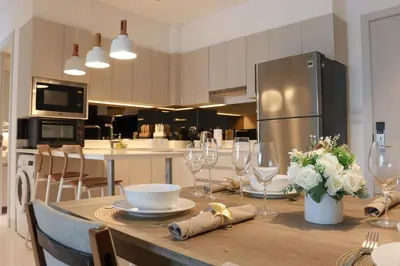 a kitchen with a table with wine glasses and a refrigerator at Cassia Residences by NLA in Bang Tao Beach