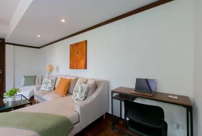 a bedroom with a couch and a desk with a laptop at Katamanda 1Bedrooms Apartment near Kata Beach in Kata Beach