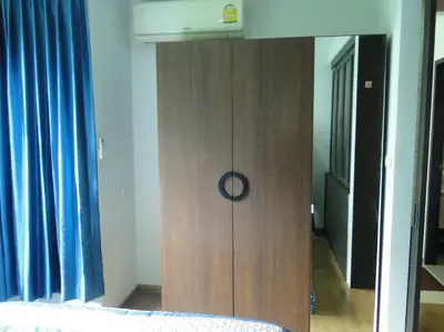a wooden cabinet in a bedroom with a bed at Apartment near Central phuket in Phuket Town