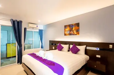 a bedroom with a large bed with purple pillows at The Great @Patong Hotel in Patong Beach