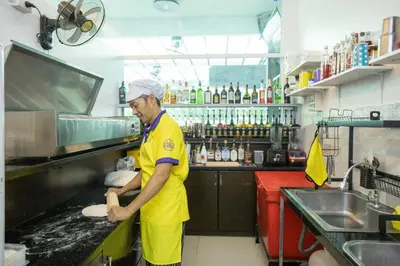 a man in a kitchen preparing food in a kitchen at The Great @Patong Hotel in Patong Beach