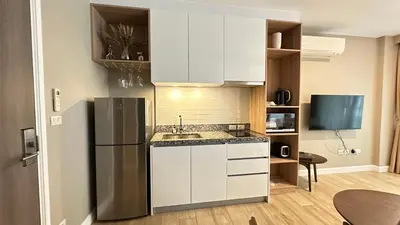 a kitchen with white cabinets and a stainless steel refrigerator at Diamond Phuket Bang Tao in Bang Tao Beach