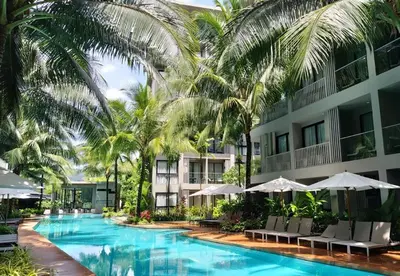 a hotel with a swimming pool with palm trees and umbrellas at Diamond Phuket Bang Tao in Bang Tao Beach