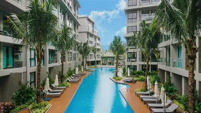 a hotel swimming pool with chaise lounges and palm trees at Diamond Phuket Bang Tao in Bang Tao Beach