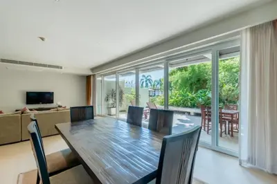 a living room with a wooden table and chairs at Poppy Beachfront Residence in Rawai Beach