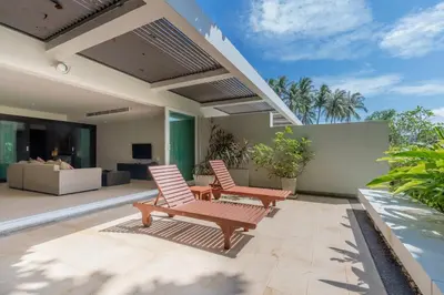 two chairs on the patio of a house at Poppy Beachfront Residence in Rawai Beach