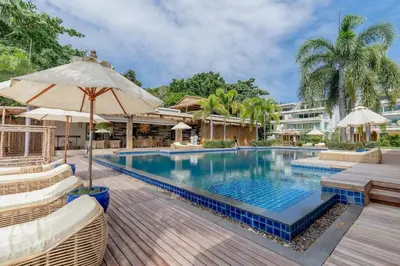 a pool at a resort with chairs and umbrellas at Poppy Beachfront Residence in Rawai Beach