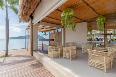 a restaurant on the beach with tables and chairs at Poppy Beachfront Residence in Rawai Beach