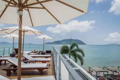 a balcony with chairs and umbrellas and the ocean at Daisy 2 Bedroom Amazing Seaview in Rawai Beach
