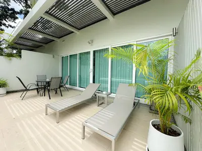 a patio with white chairs and a potted plant at Olive 1 Bedroom Beachfront in Rawai Beach