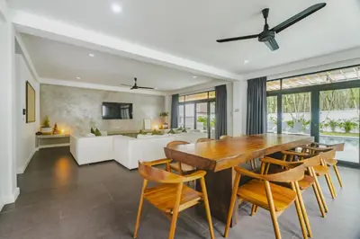 a dining room with a table and chairs and a couch at Eden Villa A Tropical Paradise Pool Villa in Rawai Beach