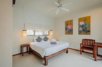 a bedroom with a white bed and a chair at Ivory Pool Villa Dreamy Villa With Sparkling Pool in Rawai Beach
