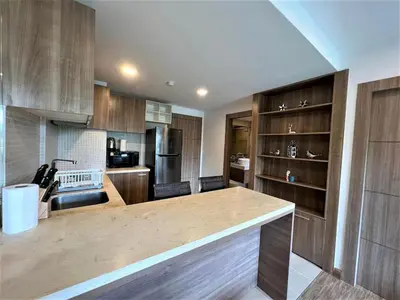 a kitchen with wooden cabinets and a large counter top at Calypso Gardens 1 Bedroom Condo In Nai Harn in Rawai Beach