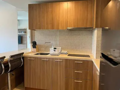 a kitchen with wooden cabinets and a sink at Calypso Gardens 1 Bedroom Condo In Nai Harn in Rawai Beach