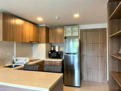 a kitchen with a stainless steel refrigerator and wooden cabinets at Calypso Gardens 1 Bedroom Condo In Nai Harn in Rawai Beach