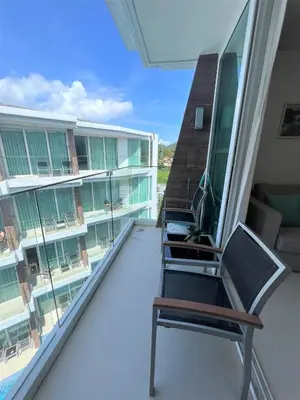 a balcony with three chairs on a building at Maroon Studio at the beachfront in Rawai Beach