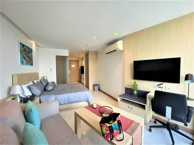 a living room with a bed and a television in a room at Maroon Studio at the beachfront in Rawai Beach