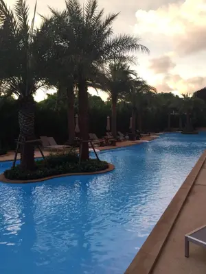a swimming pool with palm trees in a resort at Mai Khao Beach Apartments in Mai Khao Beach