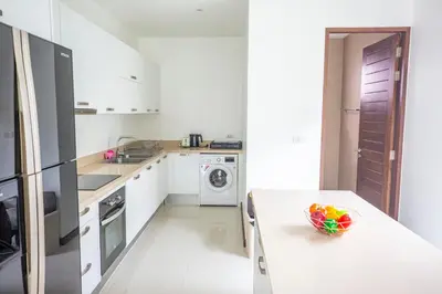 a white kitchen with a table with a bowl of fruit on it at Phuket Boutique Pool Villa-80 in Rawai Beach