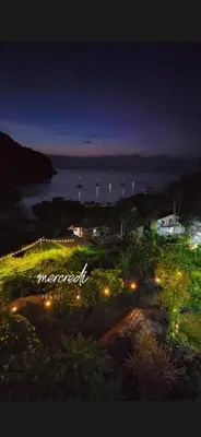 a view of the ocean at night with lights at The view Hostel in Phi Phi Don