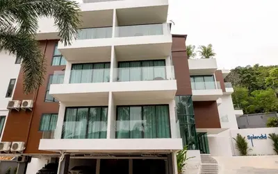 a tall building with windows and a palm tree at Cozy studio Splendid Condo by Lofty in Kata Beach