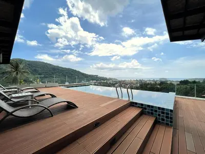 a swimming pool with chairs on a wooden deck at Cozy studio Splendid Condo by Lofty in Kata Beach