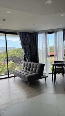 a living room with a couch in front of windows at Laguna Sky Park Corner 1 Bedroom in Bang Tao Beach