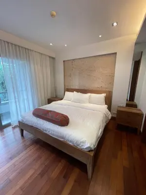 a bedroom with a large bed with a wooden floor at Naithon beach WERT in Phuket Town