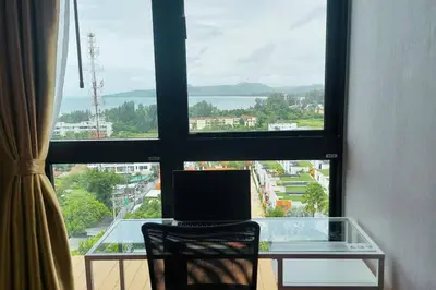 a laptop computer sitting on a glass desk in front of a window at Seaview Condo In 5 Star Resort MG1 in Phuket Town