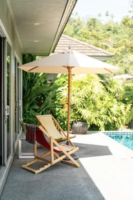 a chair and an umbrella on a porch at VILLA FLORA - North Phuket, Naiyang Beach area in Nai Yang Beach