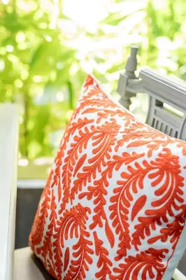 a red and white pillow sitting on a chair at VILLA FLORA - North Phuket, Naiyang Beach area in Nai Yang Beach