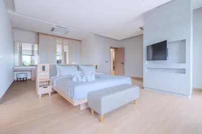 a white bedroom with a white bed and a television at The Salin Seaview Villas in Kata Beach