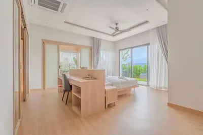 a bedroom with a desk and a bed and a bed and window at The Salin Seaview Villas in Kata Beach