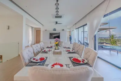 a dining room with a long table and chairs at The Salin Seaview Villas in Kata Beach