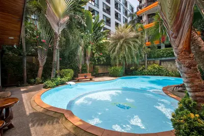 a large swimming pool in a courtyard with palm trees at 1 bdr Apartment Naiharn Beach Condo by CapitalPro in Phuket Town