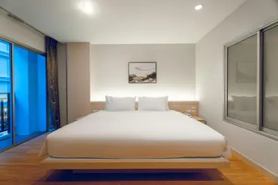 a bedroom with a white bed and a large window at Di Yana Patong in Patong Beach