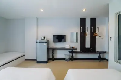 a room with a desk and a table with a refrigerator at Di Yana Patong in Patong Beach