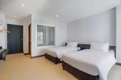 a bedroom with two beds and a window at Di Yana Patong in Patong Beach