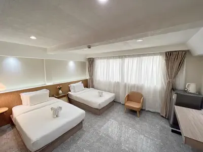 a hotel room with two beds and a television at Upsea patong in Patong Beach