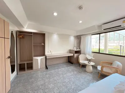 a room with a bed and a desk and chairs at Upsea patong in Patong Beach