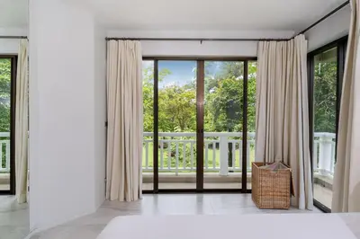 a bedroom with sliding glass doors with a view of a garden at Spacious 2BR Apartment ALM 2223 in Laguna, 10 min from BangTao Beach in Bang Tao Beach