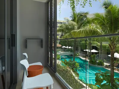 a balcony with a view of a pool and palm trees at La Green Hotel and Residence in Bang Tao Beach