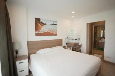 a bedroom with a white bed and a desk at Calypso Condo Rawai Nai Harn beach in Rawai Beach