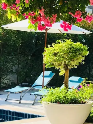 a table and chairs with an umbrella next to a pool at Master Bedroom with private bathroom and kitchen in Phuket Town