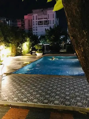 a swimming pool at night in a city at Master Bedroom with private bathroom and kitchen in Phuket Town