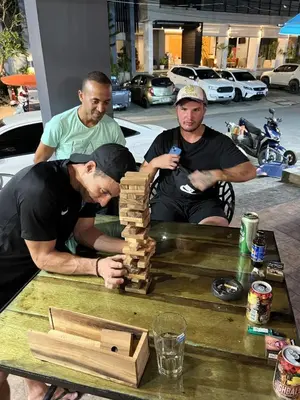 three men standing around a table playing with a wooden block at Hangover Aonang in Ao Nang Beach
