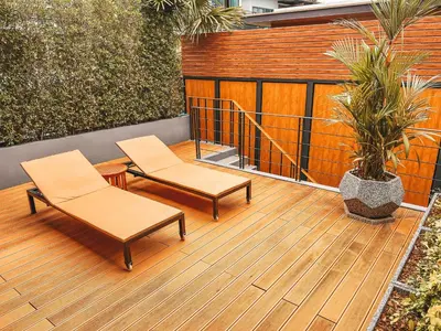 a wooden deck with two chairs and a plant at Le Villa Residence in Phuket Town