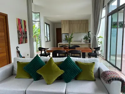 a living room with a couch with green pillows at Lada Pool Villa in Bang Tao Beach